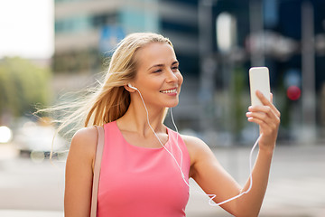 Image showing happy young woman with smartphone and earphones