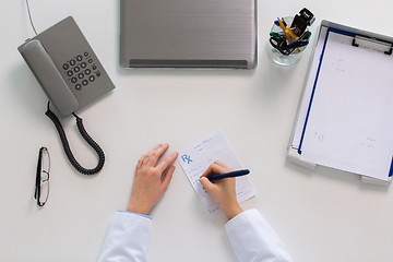 Image showing doctor hands writing prescription at table