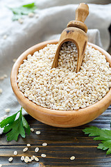 Image showing Wooden scoop in bowl with dry pearl barley.