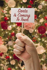 Image showing Hand Holding Santa Is Coming To Town Card In Front of Decorated 