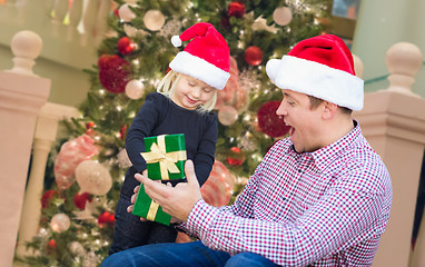 Image showing Happy Young Girl and Father Wearing Santa Hats Opening Gift Box 