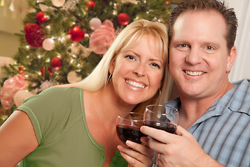 Image showing Caucasian Couple Holding Wine Glasses In Front of Decorated Chri