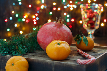 Image showing Pomegranate, tangerines and Christmas lights.