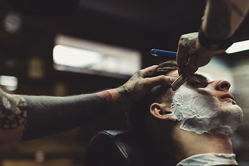 Image showing Barber shaving client