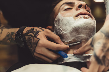 Image showing Barber shaving client