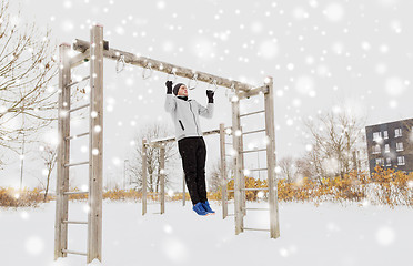 Image showing young man exercising on horizontal bar in winter