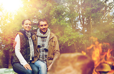 Image showing happy couple sitting on bench near camp fire