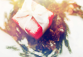 Image showing close up of christmas gift and fir wreath on snow