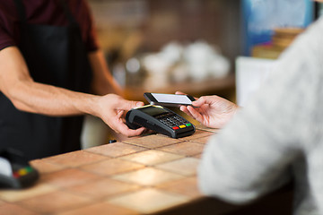 Image showing hands with payment terminal and smartphone at bar