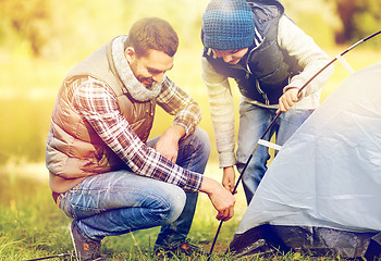 Image showing happy father and son setting up tent outdoors