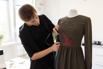 Image showing fashion designer with dummy making dress at studio