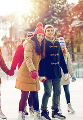 Image showing happy friends ice skating on rink outdoors