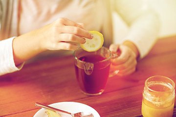 Image showing close up of ill woman drinking tea with lemon