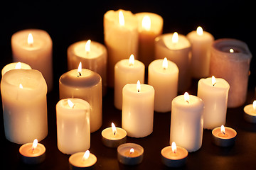 Image showing candles burning in darkness over black background