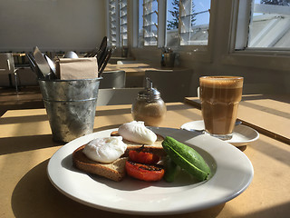 Image showing Poached eggs avocado and char-grilled tomato with latte at cafe