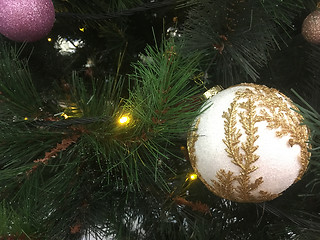 Image showing Gold embellished Christmas decoration hanging on a green tree