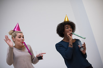 Image showing smiling women in party caps blowing to whistles