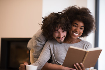 Image showing multiethnic couple hugging in front of fireplace