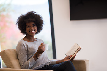 Image showing black woman reading book  in front of fireplace