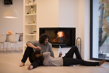 Image showing multiethnic couple using tablet computer on the floor