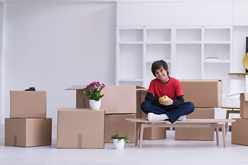 Image showing boy sitting on the table with cardboard boxes around him