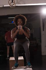 Image showing black female athlete is performing box jumps at gym