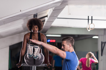 Image showing black woman doing parallel bars Exercise with trainer