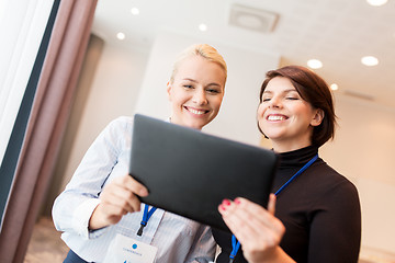 Image showing businesswomen with tablet pc and conference badges