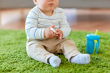 Image showing baby boy on floor and eating rice cracker at home