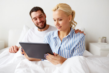 Image showing smiling happy couple with tablet pc in bed at home