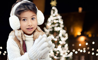 Image showing happy girl wearing earmuffs over christmas lights