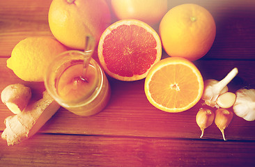 Image showing honey, citrus fruits, ginger and garlic on wood