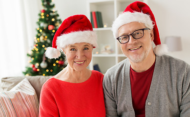 Image showing happy senior couple in santa hats at christmas