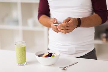 Image showing man with smartphone having breakfast at home