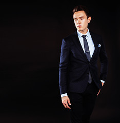 Image showing young pretty business man standing on black background, modern h