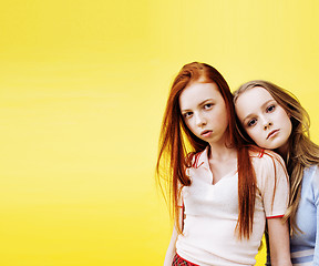 Image showing lifestyle people concept: two pretty stylish modern hipster teen girl having fun together, happy smiling making selfie close up on yellow background, diverse type girls