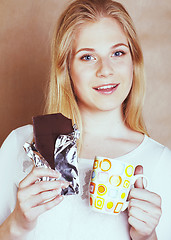 Image showing young cute blond girl eating chocolate and drinking coffee close