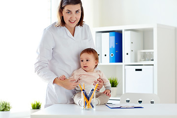 Image showing happy doctor or pediatrician with baby at clinic