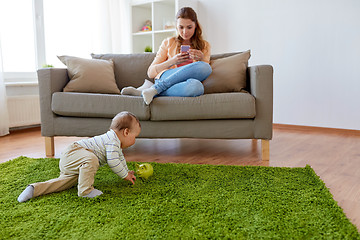 Image showing mother with smartphone and baby playing at home