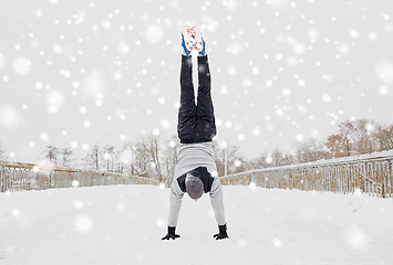 Image showing young man doing handstand in winter