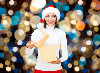 Image showing smiling woman in santa hat opening christmas gift