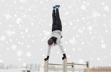 Image showing young man exercising on parallel bars in winter