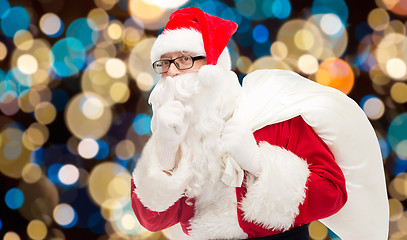 Image showing santa claus with gifts bag over christmas lights