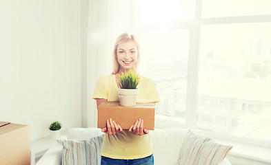 Image showing smiling young woman with cardboard box at home