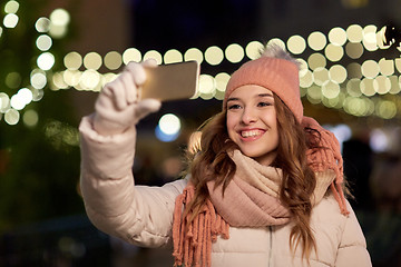 Image showing young woman taking selfie over christmas tree