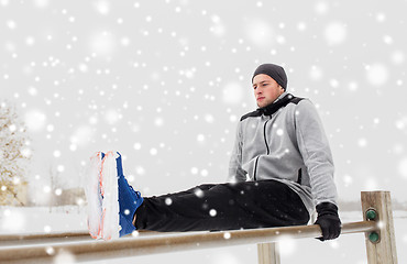 Image showing young man exercising on parallel bars in winter