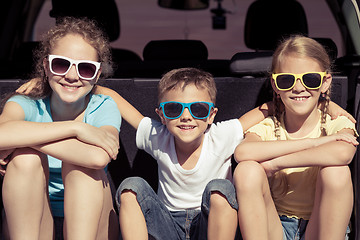 Image showing Happy brother and his two sisters are sitting in the car at the 