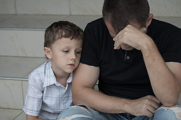 Image showing Portrait of young sad little boy and father sitting outdoors at 