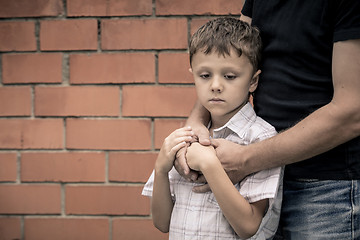 Image showing Portrait of young sad little boy and father sitting outdoors at 