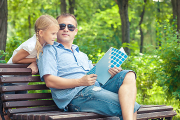 Image showing Father and daughter  playing at the park on bench at the day tim